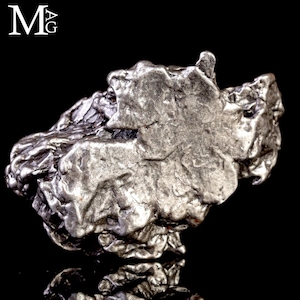 May include: A metallic silver-toned meteorite fragment with a highly irregular, textured surface featuring deep crevices and raised ridges. The object displays a dull, matte finish with varied geometric contours and a distinct, rugged appearance.
