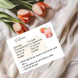 May include: A recipe card for a Paloma cocktail with a watercolor illustration of the drink. The recipe includes 2 ounces of tequila, 3 ounces of grapefruit soda, 1/2 ounce of lime juice, a pinch of salt, and a lime wheel. The instructions are to add the tequila, lime juice, and salt to a glass, fill with ice, top with grapefruit soda, stir, and garnish with a lime wheel.