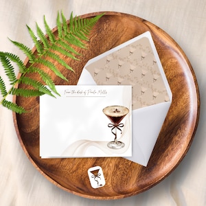 May include: Stationery set featuring a cocktail illustration. The set includes a white card with a cocktail graphic, a matching envelope with a patterned interior, and a small sticker. The text "From the desk of Paula Mills" is printed on the card.