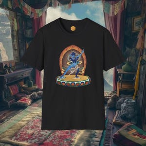 Puede incluir: Camiseta negra con una ilustración de una deidad azul. El gráfico representa una figura en una pose dinámica, sobre un fondo ornamentado. El diseño está centrado en la camiseta, mostrando una mezcla de elementos culturales y artísticos.