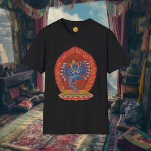 Puede incluir: Camiseta negra con una vibrante ilustración de una deidad azul con múltiples brazos, sobre un diseño circular rojo y naranja. La obra de arte es detallada y colorida, mostrando un tema espiritual o cultural.