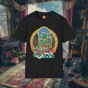 Puede incluir: Camiseta negra con una ilustración detallada de una deidad sentada de piel verde, con un halo azul y detalles dorados ornamentados. El diseño está dentro de un marco circular. La camiseta tiene cuello redondo y mangas cortas.