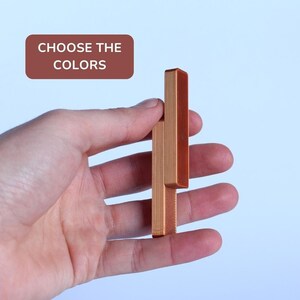 Pode incluir: Uma peça de quebra-cabeça de madeira com duas seções, uma é de cor marrom claro e a outra é de cor marrom escuro. O texto "CHOOSE THE COLORS" é visível no fundo.