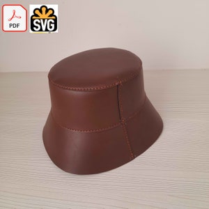 Könnte beinhalten: Ein brauner Leder-Bucket-Hut mit einer genähten Naht um die Krone und die Krempe.