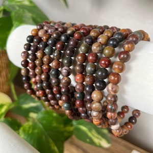 May include: A stack of bracelets made with brown, red, and black jasper beads.