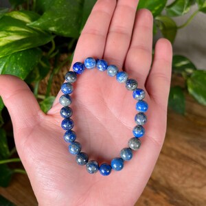 May include: A blue and grey gemstone bracelet with round beads.