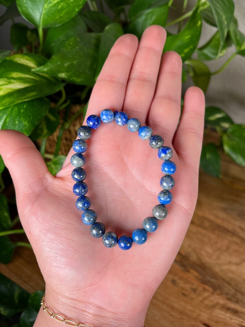 May include: A blue and grey gemstone bracelet with round beads.