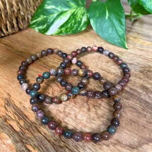 May include: Three layered bracelets made of brown, red, and green jasper beads.