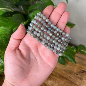 May include: A stack of six grey labradorite gemstone bracelets with a silver sheen.