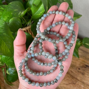 May include: A set of five grey and blue labradorite beaded bracelets. The bracelets are stacked on top of each other and are made of small, round beads.