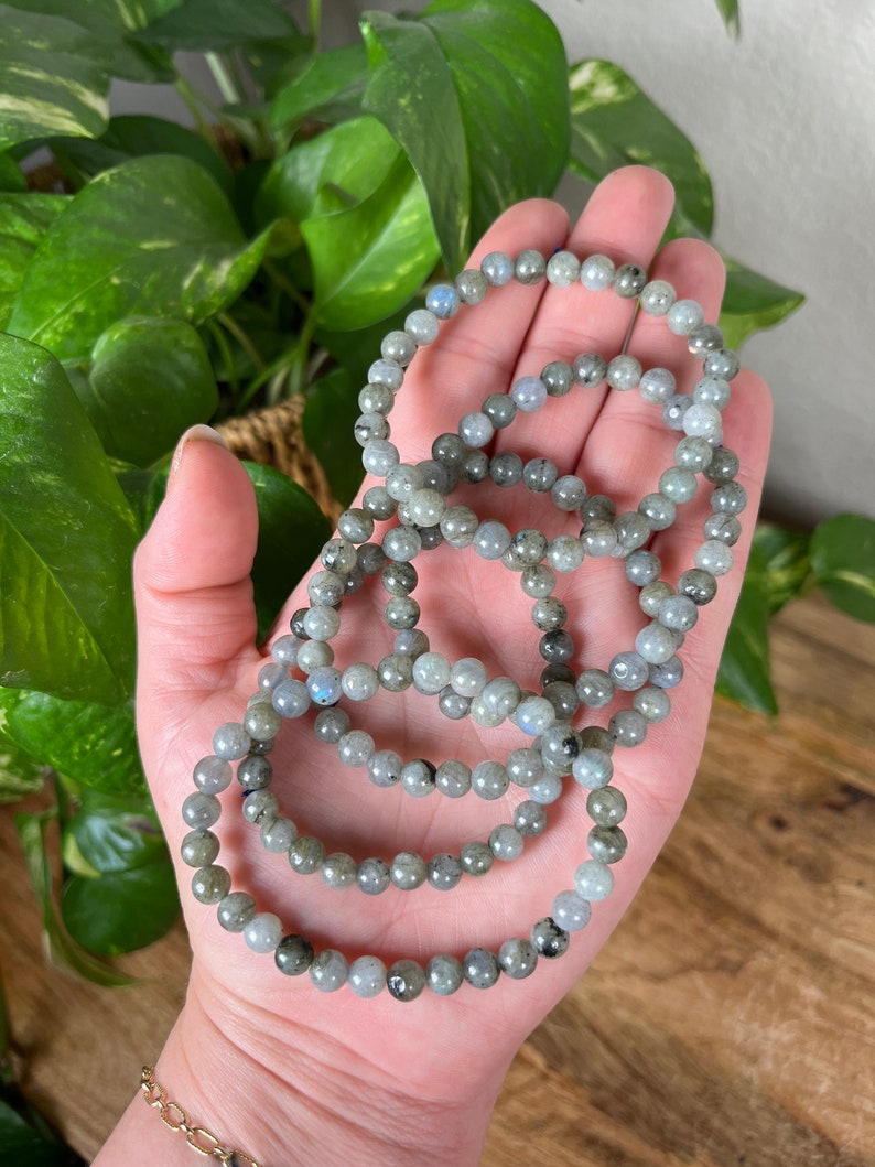 May include: A set of five grey and blue labradorite beaded bracelets. The bracelets are stacked on top of each other and are made of small, round beads.