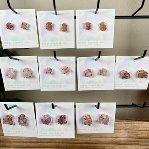 Pu&ograve; includere: Dieci paia di orecchini di cristallo su schede con il testo "Texas Crystal Co. Rare Earth Collection". Gli orecchini sono realizzati con vari cristalli, tra cui rosa, viola e arancio.