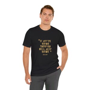 May include: Black t-shirt with the quote "IF YOU'RE GOING THROUGH HELL, KEEP GOING" in gold lettering. The quote is attributed to Churchill. The shirt is a crew neck and made of a soft material.