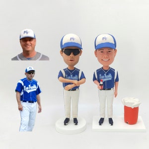 Puede incluir: Tres muñecos de béisbol personalizados, dos con gafas de sol y uno sosteniendo una lata de refresco. Los muñecos llevan uniformes de béisbol azules y blancos con el texto "New Franklin" en la parte delantera. Los muñecos están de pie sobre bases blancas.