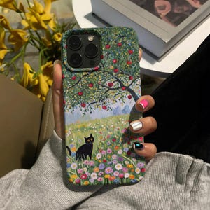 Może przedstawiać: Etui na telefon z kolorowym obrazem jabłoni, czarnego kota i pola kwiat&oacute;w. Etui ma wycięcie na aparat telefonu.