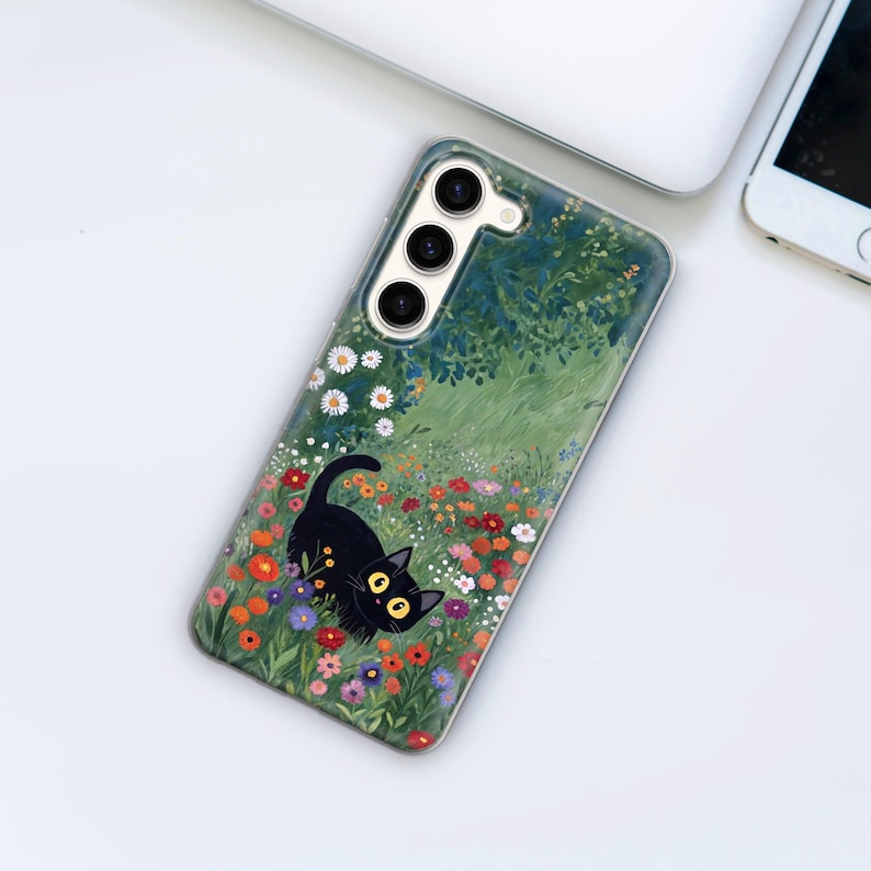 Może przedstawiać: Czarny kot z dużymi ż&oacute;łtymi oczami siedzi na polu kolorowych kwiat&oacute;w. Etui na telefon ma zielone tło z malowanym wzorem.