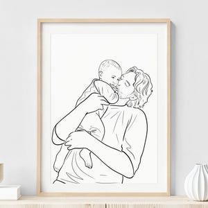 K&ouml;nnte beinhalten: Ein schwarz-wei&szlig;-Linienkunstdruck in einem hellen Holzrahmen. Das Kunstwerk zeigt eine Person, die ein Baby h&auml;lt und k&uuml;sst. Der Druck wird an einer wei&szlig;en Wand mit dekorativen Vasen und einem Holztisch ausgestellt.