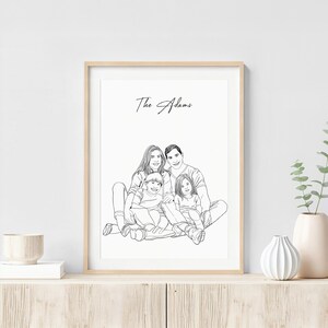 K&ouml;nnte beinhalten: Ein gerahmtes Schwarz-Wei&szlig;-Linienkunstportr&auml;t einer vierk&ouml;pfigen Familie. Das Kunstwerk zeigt eine Mutter, einen Vater und zwei Kinder, mit dem Familiennamen "The Adams" dar&uuml;ber geschrieben. Das Portr&auml;t wird in einem hellen Holzrahmen angezeigt.