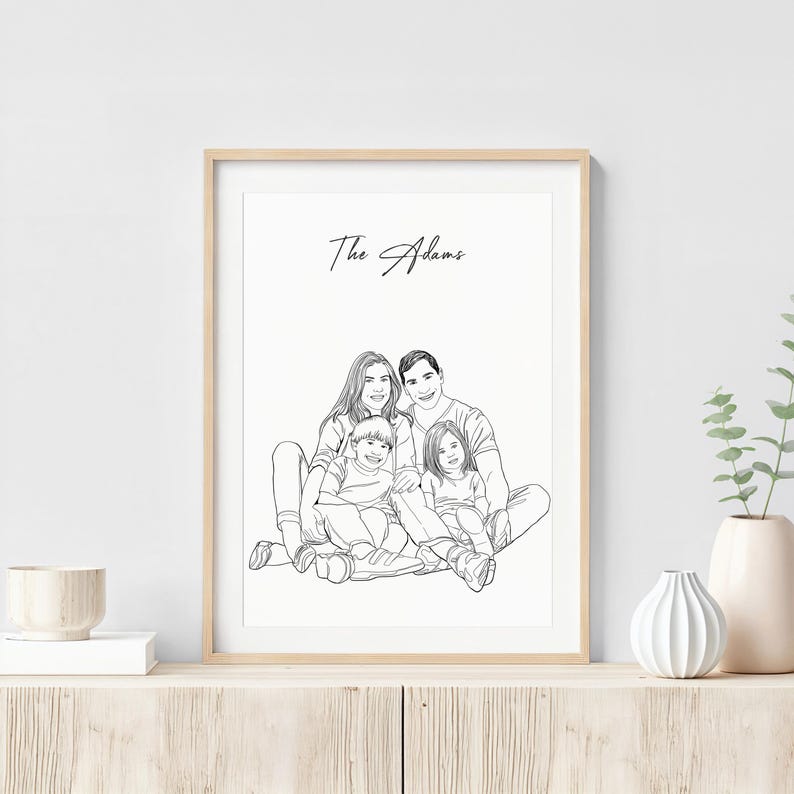 K&ouml;nnte beinhalten: Ein gerahmtes Schwarz-Wei&szlig;-Linienkunstportr&auml;t einer vierk&ouml;pfigen Familie. Das Kunstwerk zeigt eine Mutter, einen Vater und zwei Kinder, mit dem Familiennamen "The Adams" dar&uuml;ber geschrieben. Das Portr&auml;t wird in einem hellen Holzrahmen angezeigt.