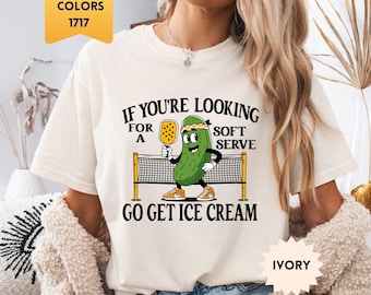 以下が含まれることがあります： 「IF YOU'RE LOOKING FOR A SOFT SERVE GO GET ICE CREAM」の文字と、ピクルスがピックルボールをしている漫画が描かれたアイボリー色のTシャツ。Tシャツはクルーネックで半袖です。「Comfort Colors 1717」と表示されています。