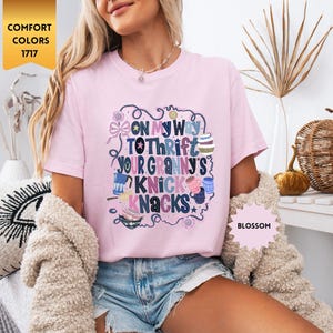 Może przedstawiać: Jasnor&oacute;żowa koszulka z napisem "ON MY WAY TO THRIFT YOUR GRANNY'S KNICK KNACKS" w fantazyjnym wzorze. Koszulka jest oznaczona jako "Blossom" i "Comfort Colors 1717".