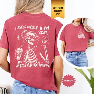 May include: Crimson t-shirt with a skeleton graphic wearing sunglasses and holding a drink, with the text "I asked myself if I'm okay, and we both started laughing." A small graphic is on the front. Comfort Colors 1717.