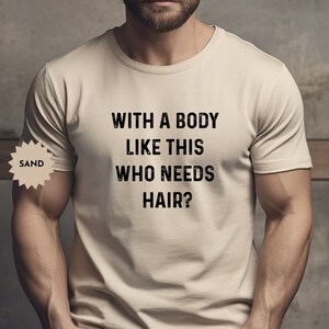 May include: A beige t-shirt with the text "WITH A BODY LIKE THIS WHO NEEDS HAIR?" printed in black.