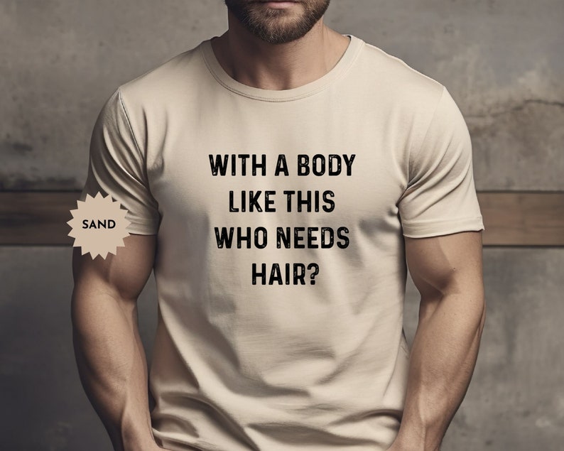 May include: A beige t-shirt with the text "WITH A BODY LIKE THIS WHO NEEDS HAIR?" printed in black.