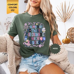Może przedstawiać: Zielona koszulka w kolorze mchu z napisem "On My Way To Thrift Your Granny's Knick Knacks" w kolorowym, fantazyjnym wzorze. Koszulka jest w stylu Comfort Colors 1717.