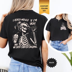 May include: Black t-shirt with a skeleton graphic wearing sunglasses and holding a drink, with the text "I asked myself if I'm okay, and we both started laughing." A smaller image shows a peace sign with roses.