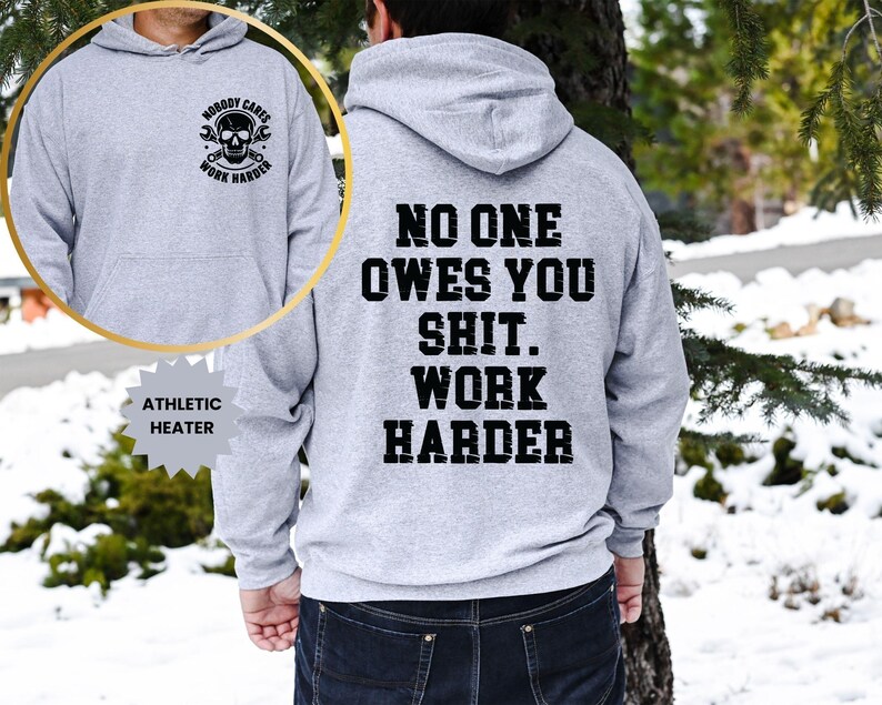Op de afbeelding: Een lichtgrijze atletische hoodie met de tekst "NO ONE OWES YOU SHIT. WORK HARDER" in het zwart op de achterkant. De voorkant heeft een cirkelvormige afbeelding met een schedel, moersleutels en de woorden "NOBODY CARES WORK HARDER".