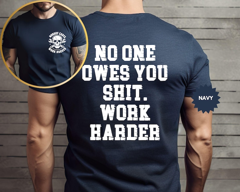 Op de afbeelding: Marineblauw t-shirt met witte tekst op de achterkant: "NO ONE OWES YOU SHIT. WORK HARDER." Een kleinere afbeelding toont de voorkant van het shirt met een schedel- en moersleutelafbeelding en de woorden "NOBODY CARES WORK HARDER."