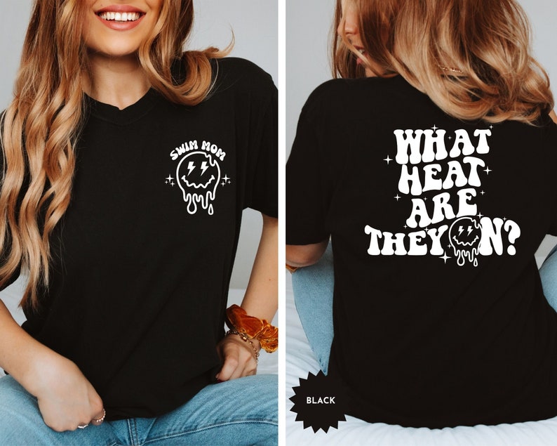 May include: Black t-shirt with a white graphic on the front that says "Swim Mom" with a dripping smiley face and lightning bolts. The back of the shirt has a white graphic that says "What heat are they on?" with a dripping smiley face.