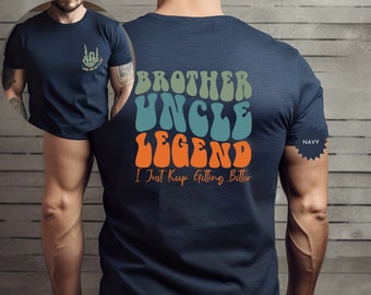 May include: A navy blue t-shirt with a retro-style graphic that reads "Brother Uncle Legend I Just Keep Getting Better" in orange, green, and blue.