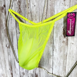 May include: A neon yellow thong made of sheer mesh fabric with thin side straps. A black rectangular tag is attached to the side, featuring the white text "jovanadesign" and the words "sexy lingerie" printed in a stylized script font.
