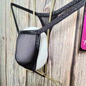 May include: Black mesh lingerie with black trim. The lingerie is hanging on a gold hanger.