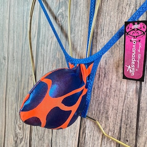 May include: A blue and orange patterned jockstrap with a blue trim. The jockstrap is hanging on a gold hanger. The tag reads "Jovanadesign Sexy Lingerie".