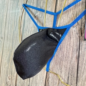 Könnte beinhalten: Schwarze Dessous mit blauem Besatz. Die Dessous hängen an einem goldenen Kleiderbügel.