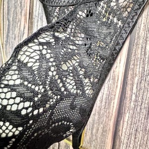 Puede incluir: Primer plano de lencer&iacute;a de encaje negro con un delicado estampado floral. El intrincado dise&ntilde;o es visible sobre un fondo claro. La lencer&iacute;a presenta finas correas y una silueta cl&aacute;sica, mostrando la detallada artesan&iacute;a.
