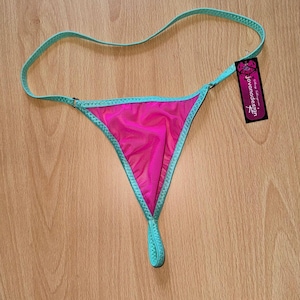 May include: Pink mesh thong with a turquoise trim. The thong has a small loop at the back. The tag says "Jovanadesign".
