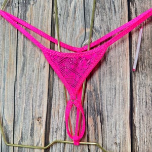 Può includere: Perizoma rosa acceso con un pannello frontale in rete e spalline delicate. La lingerie è esposta su un gancio color oro su sfondo di legno. Il perizoma presenta un design unico con un dettaglio ad anello.