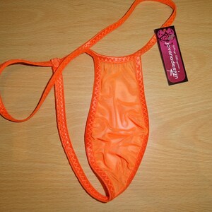 Op de afbeelding: Oranje mesh lingerie met een delicate kantversiering. De lingerie heeft een enkele band die om de nek gaat en een klein label met de tekst "Jovanadesign".
