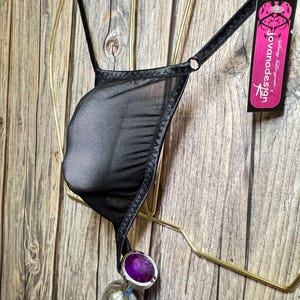 May include: Black mesh lingerie with a satin trim and a Joviana Design tag. The lingerie is hanging on a gold hanger.