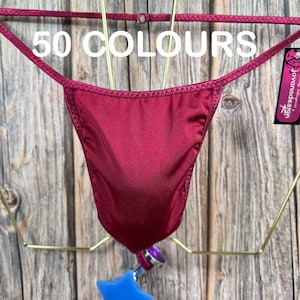 May include: A burgundy-colored, silky, thong-style underwear with a thin strap design. The underwear is hanging on a gold-colored hanger. The text "50 COLOURS" is visible in the image.