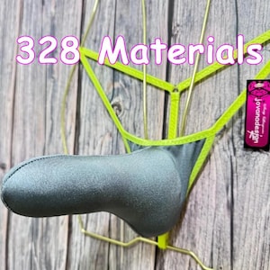 May include: A gray thong-style undergarment with neon green trim and accents. The text "328 Materials" is displayed in pink. A small tag with the brand name "jovanadesign" is visible.