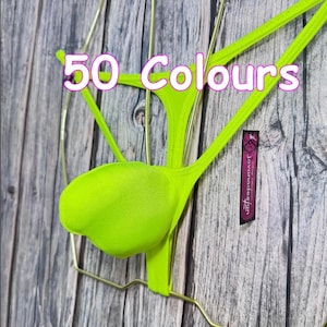 May include: A neon lime green thong with thin side straps displayed on a gold wire hanger. The text 50 Colours is printed in white with a purple outline across the top. A small black rectangular tag with the text jovanadesign is attached.