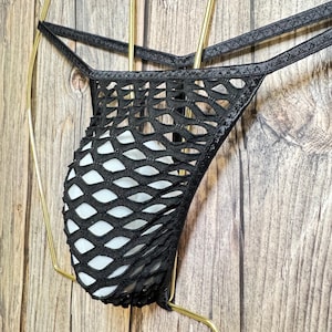 May include: Black mesh underwear with a diamond pattern. The underwear is hanging on a gold hanger.