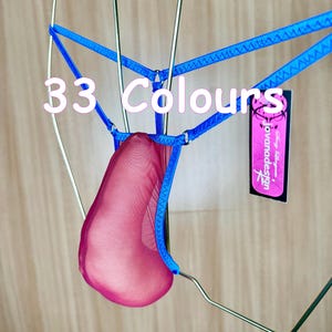 Könnte beinhalten: Ein rosa Netzbeutel mit blauen Verzierungen und einem Etikett mit der Aufschrift "Jovanadesign". Der Beutel hängt an einem Metallbügel. Der Text "33 Farben" ist auf dem Bild zu sehen.