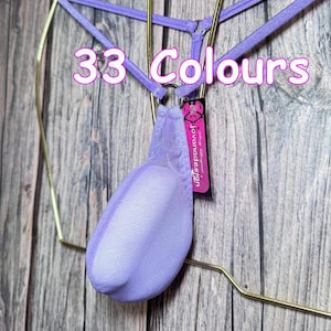 May include: A light purple mesh pouch underwear featuring thin straps and a metal ring connector. The garment includes a small black tag with the text "jovanadesign" and the overlay text "33 Colours" is visible across the upper section.