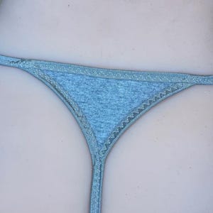 May include: A light gray thong with a delicate lace trim. The thong is made of a soft, stretchy fabric.